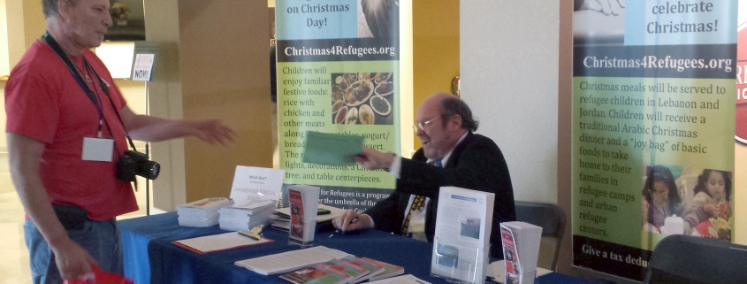An attendee at The Awakening receives information about our Christmas program. Many people visited our exhibit and either took information or spoke with me or with a volunteer.