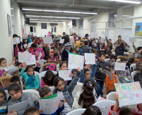 Part of the program included a coloring contest. Here children hold up their drawings hoping to win a small prize. Every child eventually received a gift.