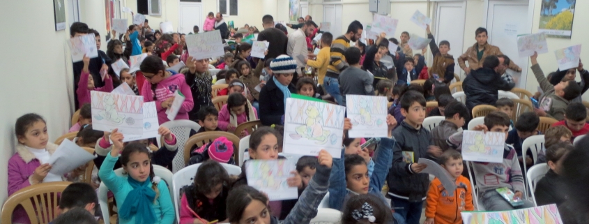 Part of the program included a coloring contest. Here children hold up their drawings hoping to win a small prize. Every child eventually received a gift.